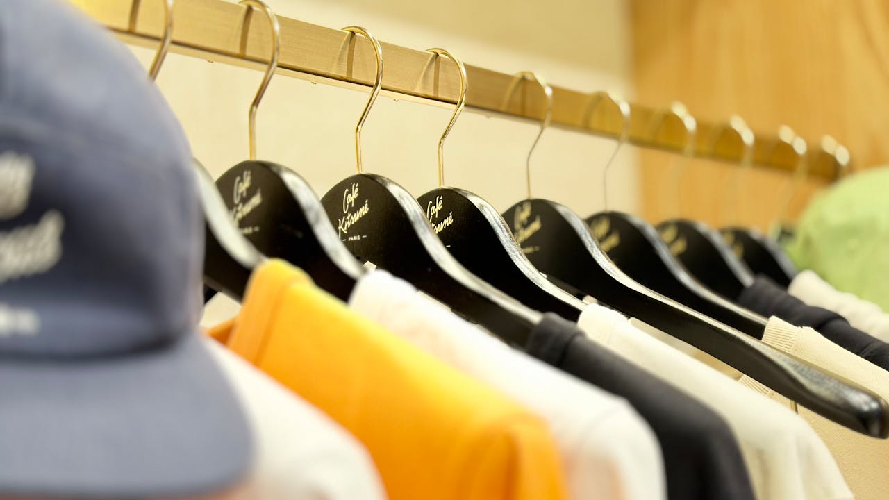 Close-up of colorful clothing hanging on black Cafe Kitsune hangers in a fashion store.